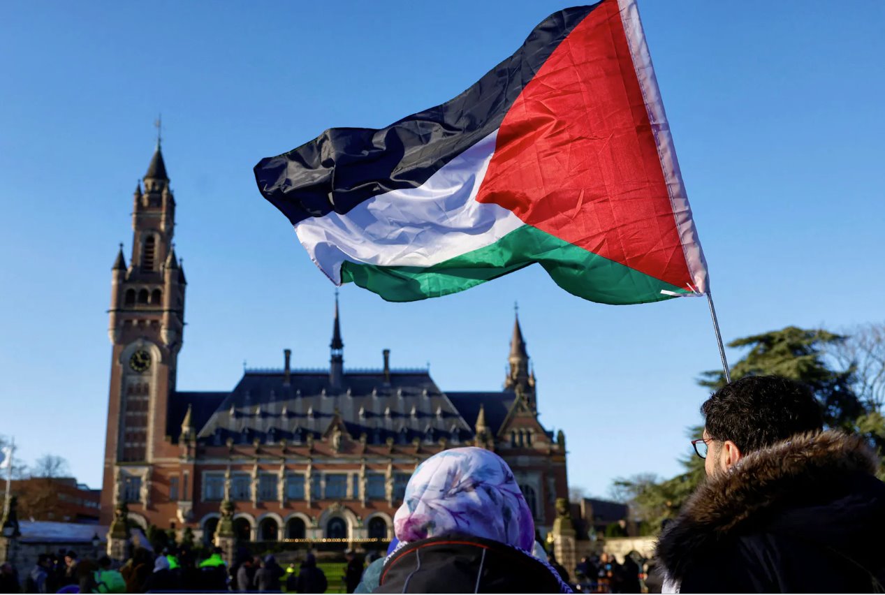 在荷兰海牙，抗议者举着巴勒斯坦国旗聚集在国际法院外，法官就针对以色列的紧急措施做出裁决，南非指控以色列在加沙的军事行动是国家主导的种族灭绝。