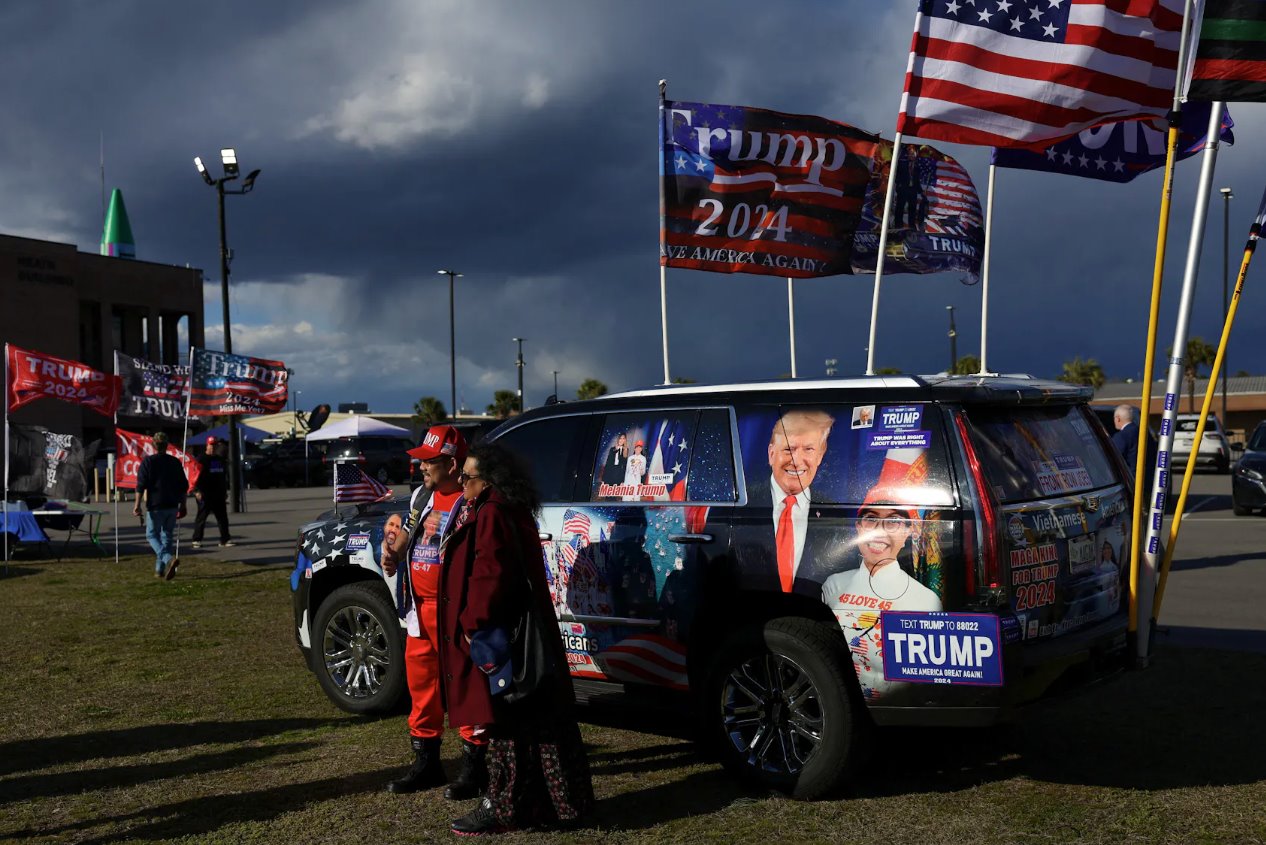 2024年2月24日，美国前总统、共和党总统候选人唐纳德·特朗普的支持者在美国南卡罗来纳州哥伦比亚举行的南卡罗来纳州共和党总统初选之夜派对前，在一辆装饰精美的汽车上摆姿势。