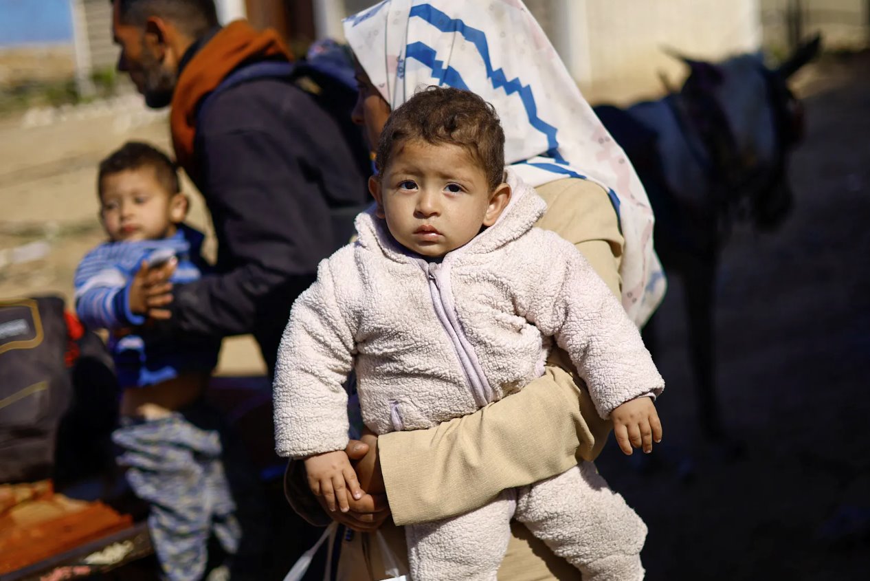 2024年3月15日，在加沙地带中部，一名怀着婴儿的妇女和其他巴勒斯坦人因以色列的军事进攻而逃离加沙北部，在以色列和哈马斯之间持续的冲突中向南迁移。