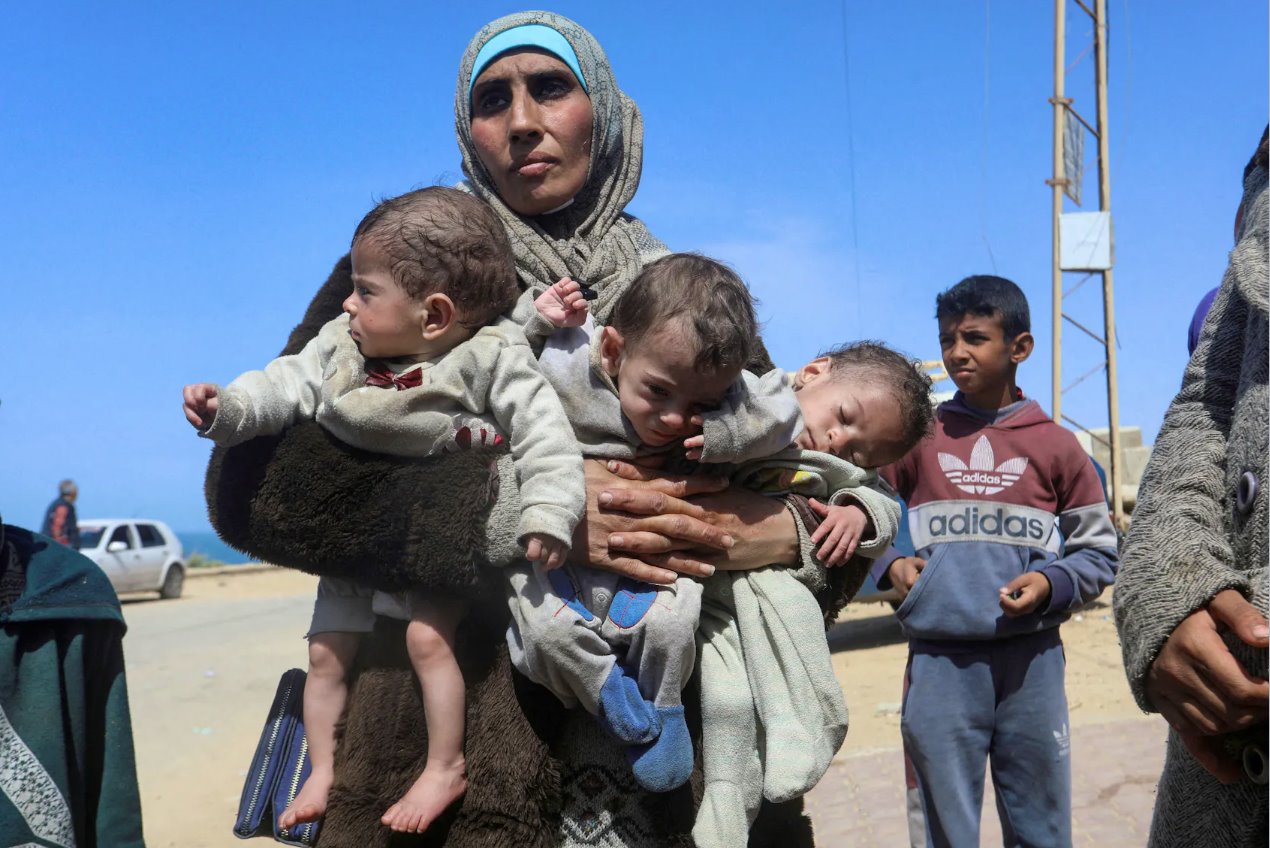 2024年3月21日，巴勒斯坦妇女诺扎·阿瓦德(NozhaAwad)带着她的三胞胎孩子在以色列袭击后逃离AlShifa医院，在加沙地带中部向南迁移。